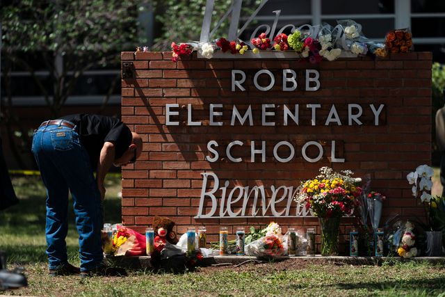 Law enforcement personnel lights a candle outside Robb Elementary School in Uvalde, Texas.